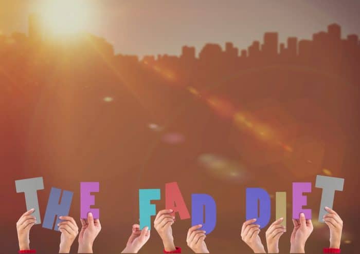 Group of people's hands holding up the words, "The Fad Diet."