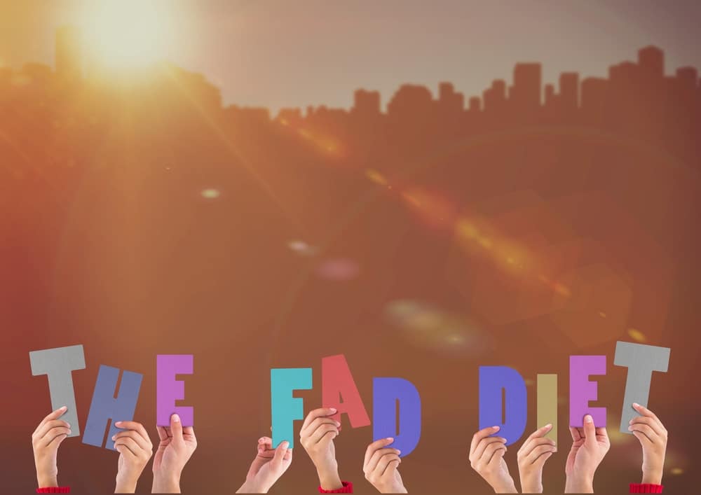 Group of people's hands holding up the words, "The Fad Diet."