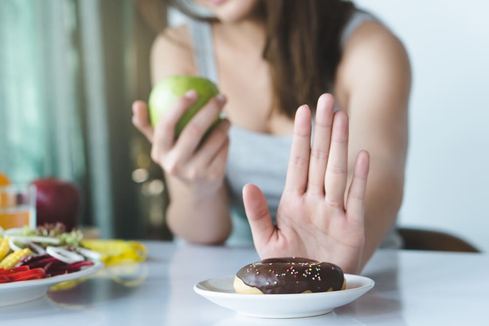 A woman pushing away an offered dessert.