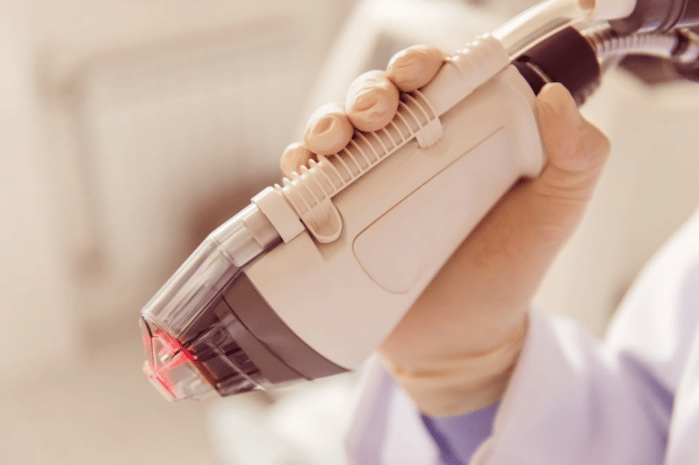 Hand of a medical professional holding a laser device.