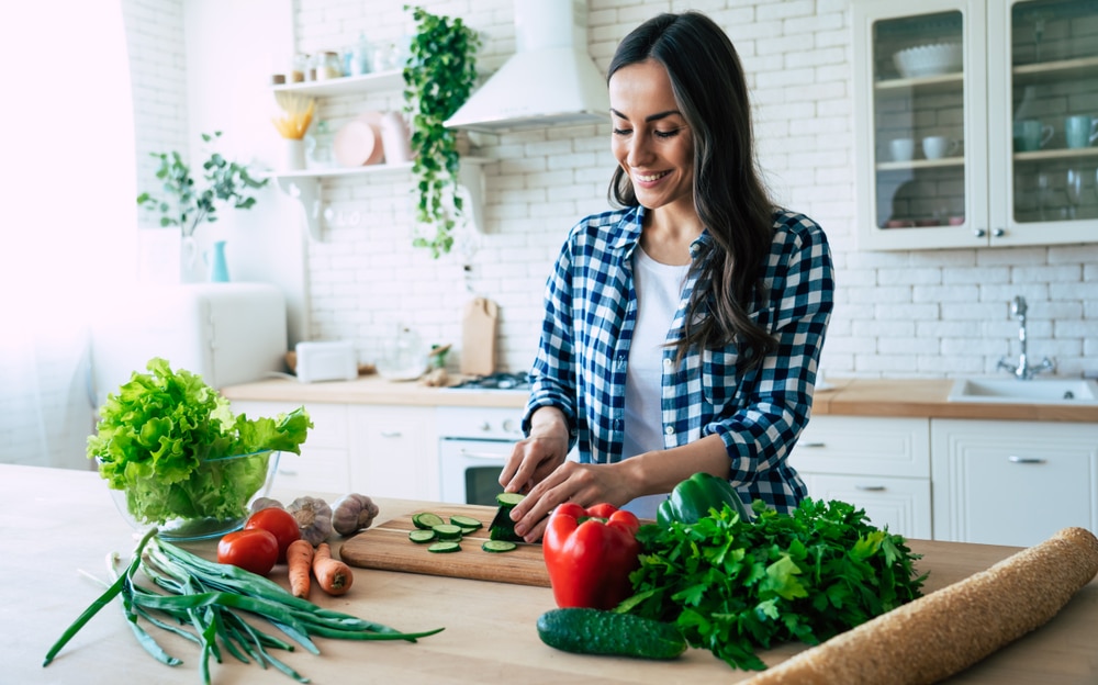 woman cutting vegetables in kitchen for healthy diet