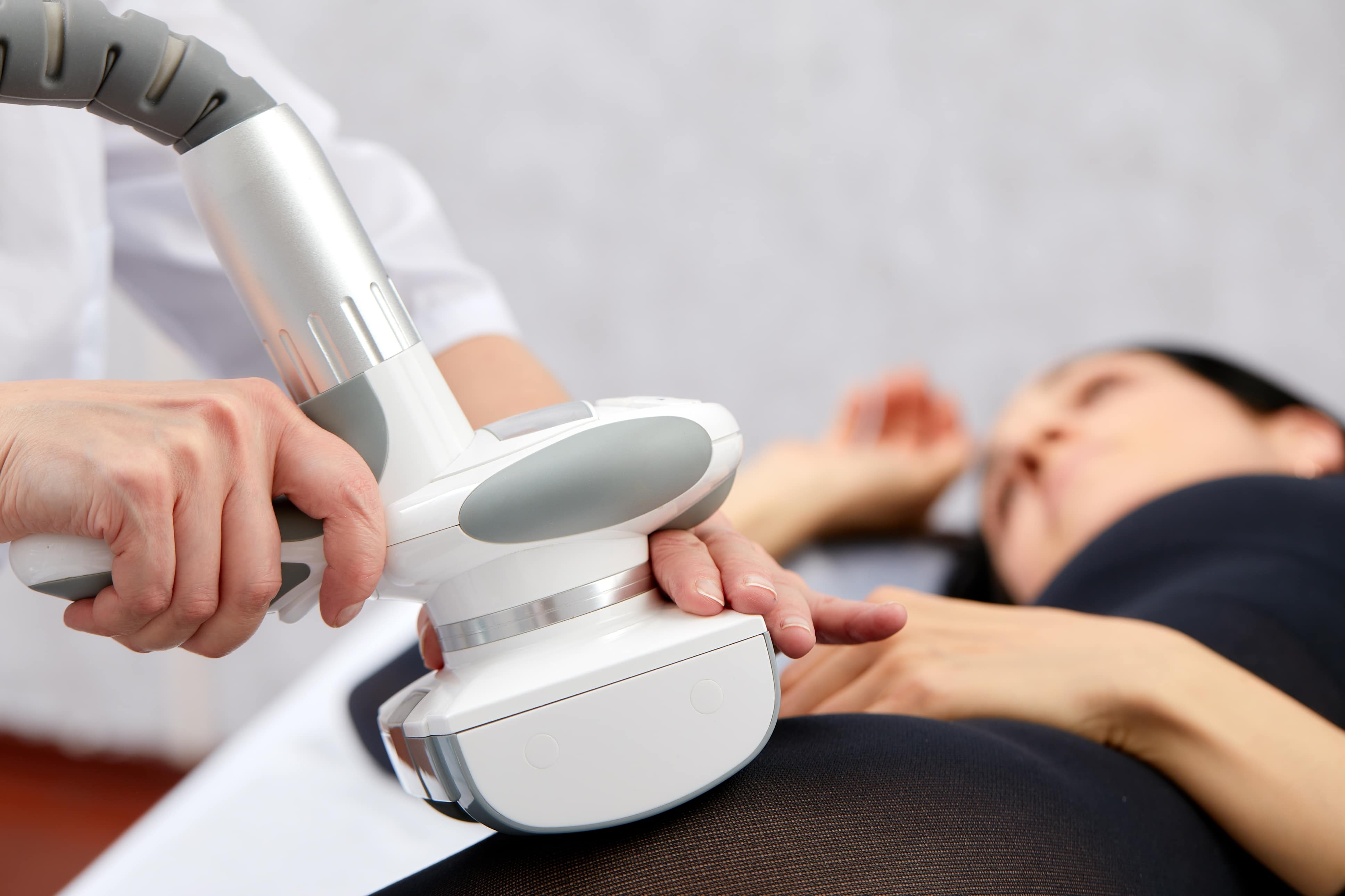Woman lying on procedural table for laser lipolysis weight loss session
