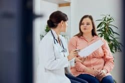 Woman concerned over weight speaking with her doctor about possible treatments such as laser lipolysis.