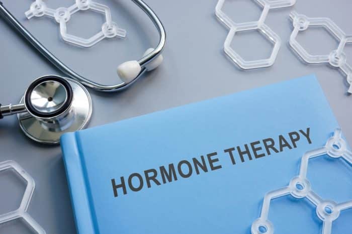 A book entitled "Hormone Therapy" on a table near a stethoscope and plastic hexagons that are made for molecular models.