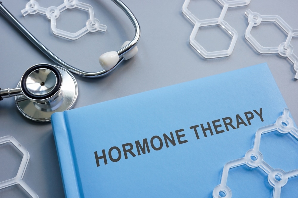 A book entitled "Hormone Therapy" on a table near a stethoscope and plastic hexagons that are made for molecular models.