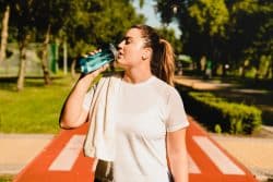 Young woman drinking water after exercising during weight loss journey.
