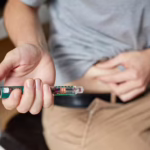 Person using a GLP-1 weight loss injection pen as part of a medical weight management treatment